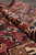 Rolled edge showing thick wool pile depth, burgundy field and ivory border in raking light
