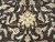 Center detail of a cream and butter yellow palmette surrounded by curling leaves on brown ground