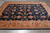 9'3" x 11'8" Zigler rug photographed on grey tile floor showing navy field and rust border