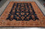 Tan main border with rust rosettes frames the deep navy floral field of this wool rug