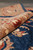 Rolled edge close-up showing the plush organic wool pile in navy, rust and camel tones