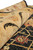 Rolled rug showing plush wool pile depth, gold border scrollwork and red flower detail