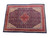 Angled studio view of a large navy and red Mahal rug with ivory spandrels