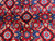 Macro detail of red pile with blue rosettes, ivory leaf motifs and turquoise accents