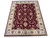 Angled studio photograph of hand-knotted Indian Agra rug showing wine field and wide ivory floral border