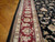 Detail of burgundy main border with ivory guard stripes and palmettes beside black floral field