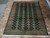 Overhead shot of the large green wool area rug with ivory fringe and brown striped borders