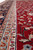 Close-up of light blue guard border with ivory stripe against deep red pile and silk sheen