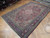 6'4 x 10 Persian Heriz rug photographed at an angle showing navy border and ivory corner spandrels