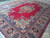 Angled view showing the open ruby field and dense navy border of this large Persian rug