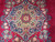 Medallion close-up showing rose bouquets, turquoise outlines and fine wool pile on red ground