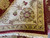 Folded ivory border corner revealing dense knotting, gold guard band and clean cotton fringe