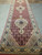 Perspective view down the wool and silk runner, medallions repeating toward the far end of warehouse