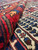 Fold-back shot revealing dense natural wool pile, thick handle and rich antique red border
