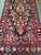 Red vase motif issuing flowering branches across the black field of this Sarouk runner
