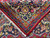 Back of the rug folded to show tight hand-knotting, white cotton fringe and clear design