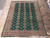 Full 8'3" x 11' hand-knotted wool rug laid flat, green field framed by ivory borders