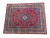 Angled studio shot showing the entire hand-knotted wool rug, navy floral border framing a burgundy field