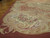 Angled corner detail showing dusty red border, acanthus scrolls and pink rose bouquets on flat wool weave