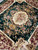 Corner perspective showing ivory medallion, burgundy frame and cascading floral sprays in gold