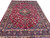 Large 10x13 Persian Mashad rug photographed from a corner, showing scrolling palmettes and vines