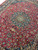 10' x 13' Persian Mashad rug photographed at an angle showing the full floral field and medallion