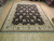 9' x 12' Indian hand-knotted rug photographed at an angle showing ivory guard borders and fringe