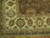 Corner detail of the ivory main border with green, blue and salmon rosettes above fringe