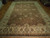 Large hand-knotted brown and gold wool area rug photographed lengthwise across a hardwood floor