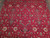 Close-up of ivory palmettes, diamond rosettes and navy outlined leaves across the crimson red field