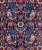 Close-up of ivory paisley boteh, red rosettes and palmettes across the midnight blue wool pile