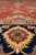 Low angle macro of border rosette in gold and garnet against deep navy wool pile