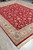 Corner perspective of red floral living room rug with beige main border and cotton fringe