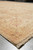 Corner and fringe detail of the Chobi Peshawar rug resting on a pale concrete floor