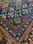 Indigo blue spandrel close-up displaying olive and rust tribal motifs beside multiple guard border stripes