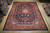 Room size 9'11" x 13'3" Sarough rug laid flat on wood floor in warehouse