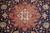 Close up of ivory eight petal rosette inside red orange stepped medallion on navy