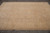 Neutral earth tone Peshawar rug photographed lengthwise on grey tile floor showing soft beige field