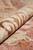 Rolled corner of the wool rug revealing dense pile depth and soft coral reverse tones