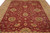 Overhead close view of the burgundy field, gold rosettes and teal flower centers across the rug