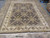 Hand-knotted Oriental rug photographed on warehouse floor showing black field and wide ivory floral border