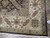 Corner detail showing ivory border medallions, olive brown guard stripe and black selvage binding