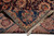 Folded corner revealing tight hand-knotted back, navy border rosette and ivory cotton fringe ends