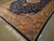 Side angle of navy and gold area rug, silky sheen catching light across the border
