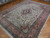 10x13 wool and silk Tabriz rug angled on parquet, ivory field catching light across the pile