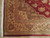 Corner detail showing beige main border, sage rosettes, burgundy selvage and white cotton fringe