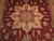 Close up of ivory and brown star medallion with pink rosette on burgundy wool pile