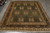 7'11" x 9'10" hand-knotted wool rug displayed on grey tile floor showing full green field
