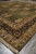 Low angle corner shot highlighting thick wool pile, golden border rosettes and ivory cotton fringe