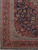 Corner detail showing red spandrel, layered guard stripes, border rosettes and the ivory fringe